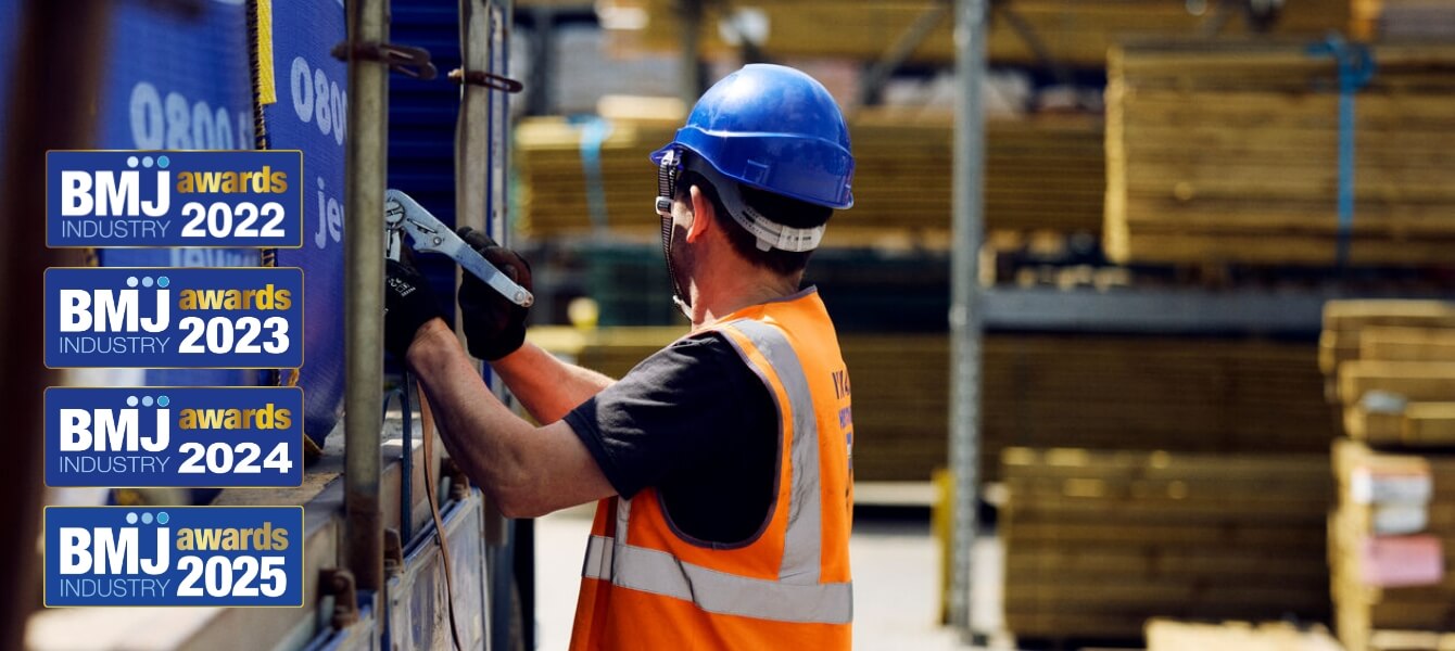 An image of a man unloading timber from a lorry. He is facing away from the camera. On the left side, there is the four logos from the previous Builders Merchants Journal (BMJ) awards.